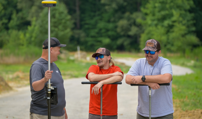 Jeff Vaughan, Jordan Harris, and Trent Bostic stand together with soil augers on a worksite.