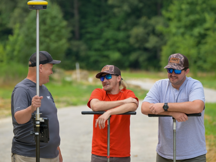 Jeff Vaughan, Jordan Harris, and Trent Bostic stand together with soil augers on a worksite.